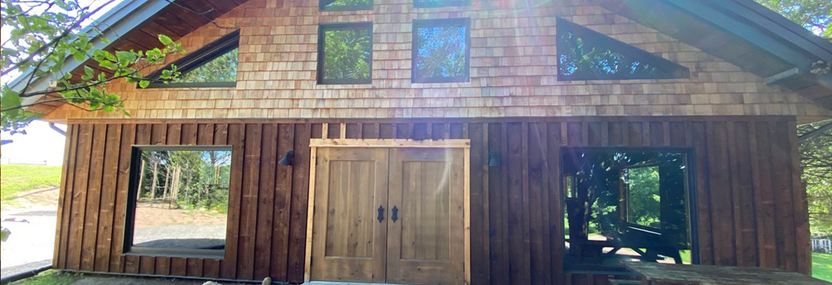Tab 2: A ray of sunlight shines over a rustic building with new wood siding.