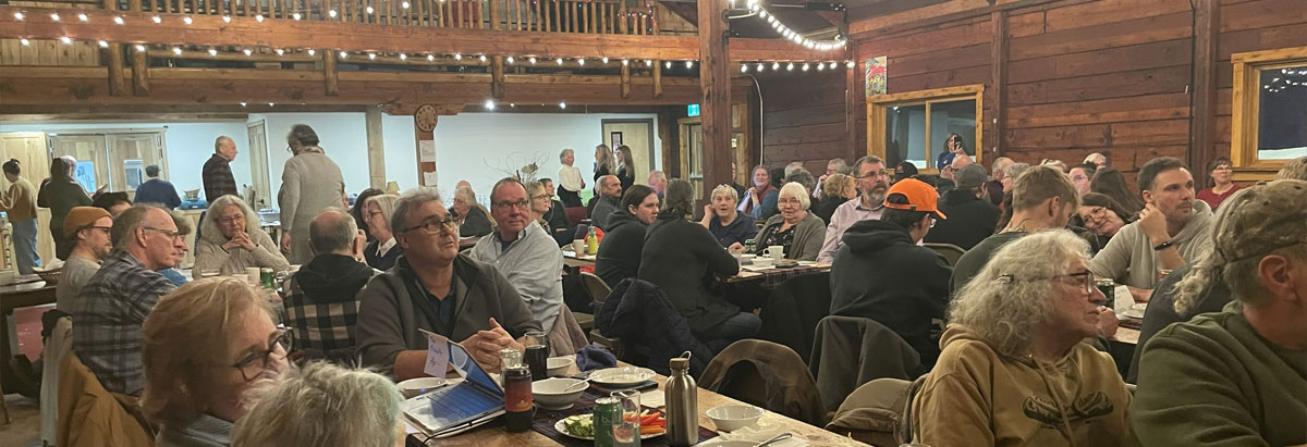 Tab 4: A group of people eating a meal in a gathering hall with string lights overhead.
