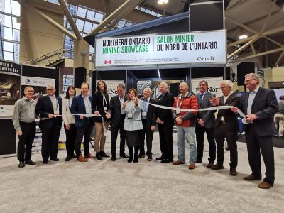 MP Viviane Lapointe cuts the ribbon to celebrate the opening of the Northern Ontario Mining Showcase. Several people stand next to her clapping and smiling.