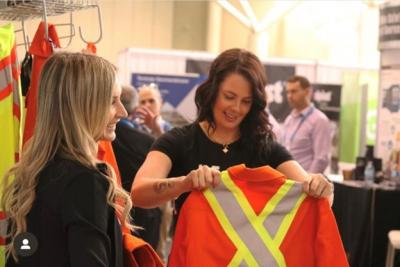 A woman holding up a safety jacket while another looks on